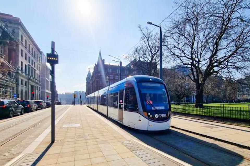 Edinburgh Tram at the platform in St Andrew Square with sun shining in a clear blue sky
